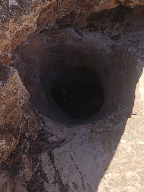 A round dark hole in grey limestone rock: the Caiguna Blowhole