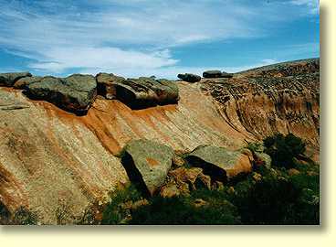 Pildappa Rock is a unique inselberg. One of its impressive features is a decaying granite sheet structure. Note the water seepage below the decaying granite sheet. Water greatly affects chemical weathering of granite surfaces.